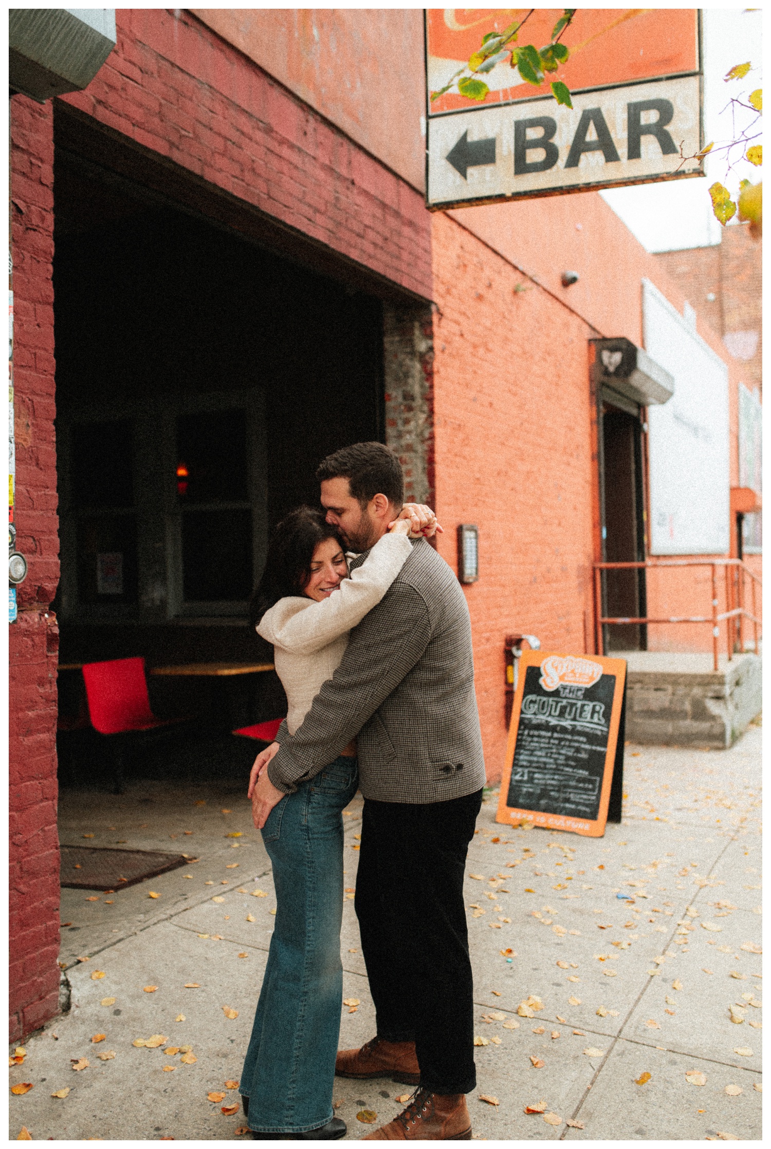 Engaged couple laughing and hugging as they walk down the streets of Williamsburg Brooklyn to their favorite bar. Brooklyn Wedding Photographer. Parr Photo Co