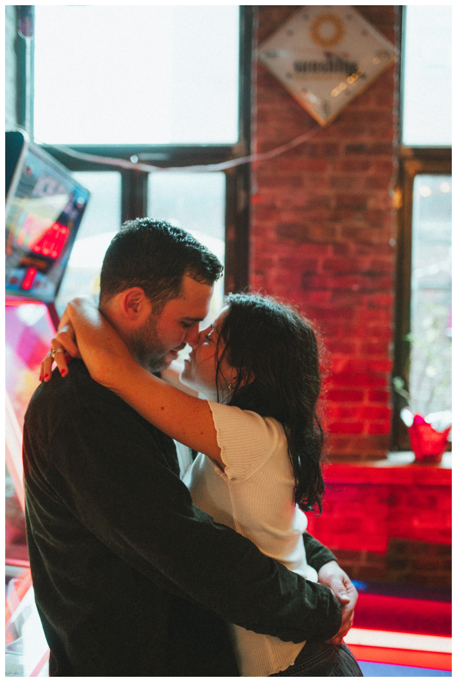Engaged couple at Sunshine Laundromat Pinball Bar in Greenpoint Brooklyn playing pinball. Brooklyn Wedding Photographer. Parr Photo Co.