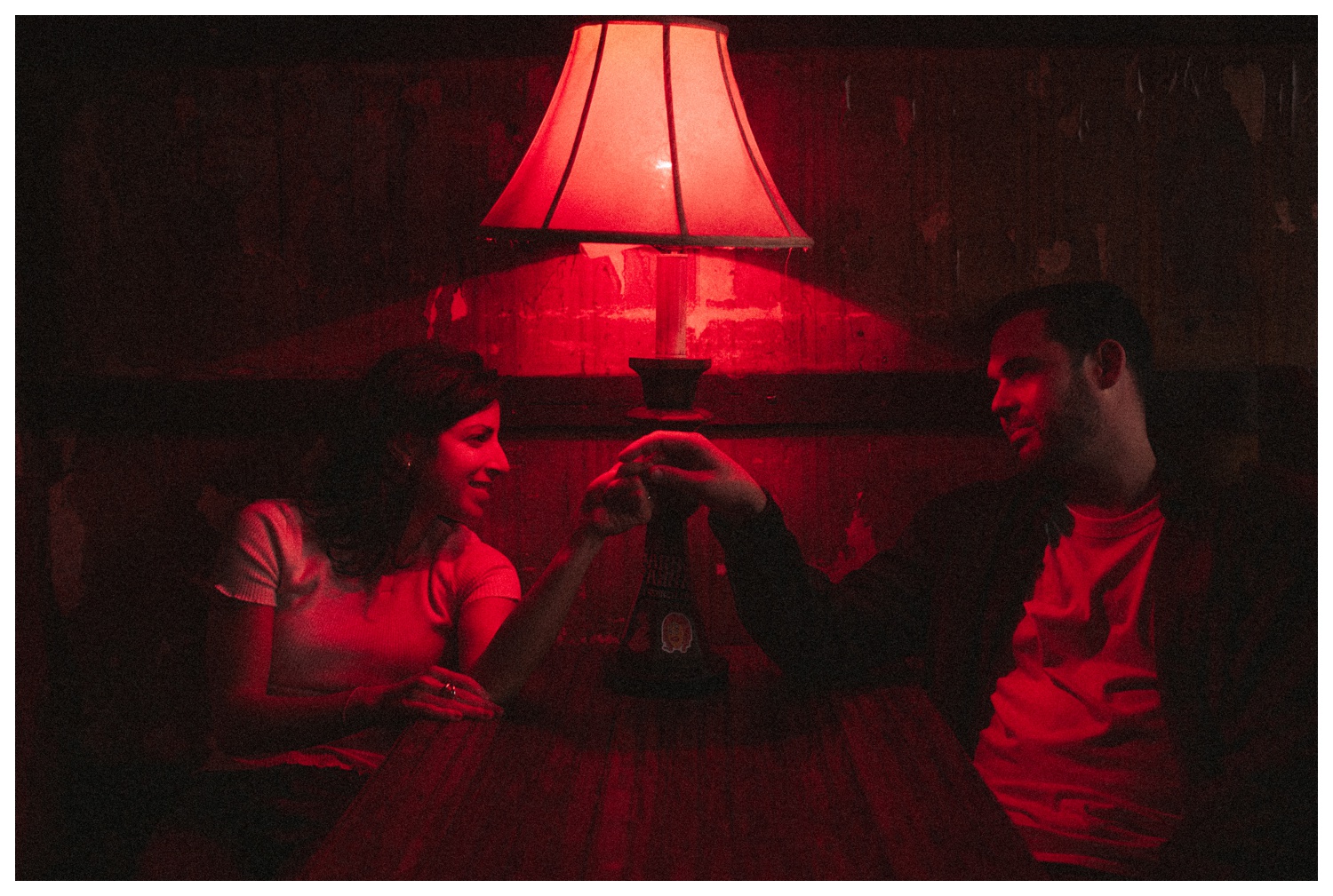 Engaged couple sitting in a bar under red light in Greenpoint Brooklyn. Brooklyn Wedding Photographer. Parr Photo Co