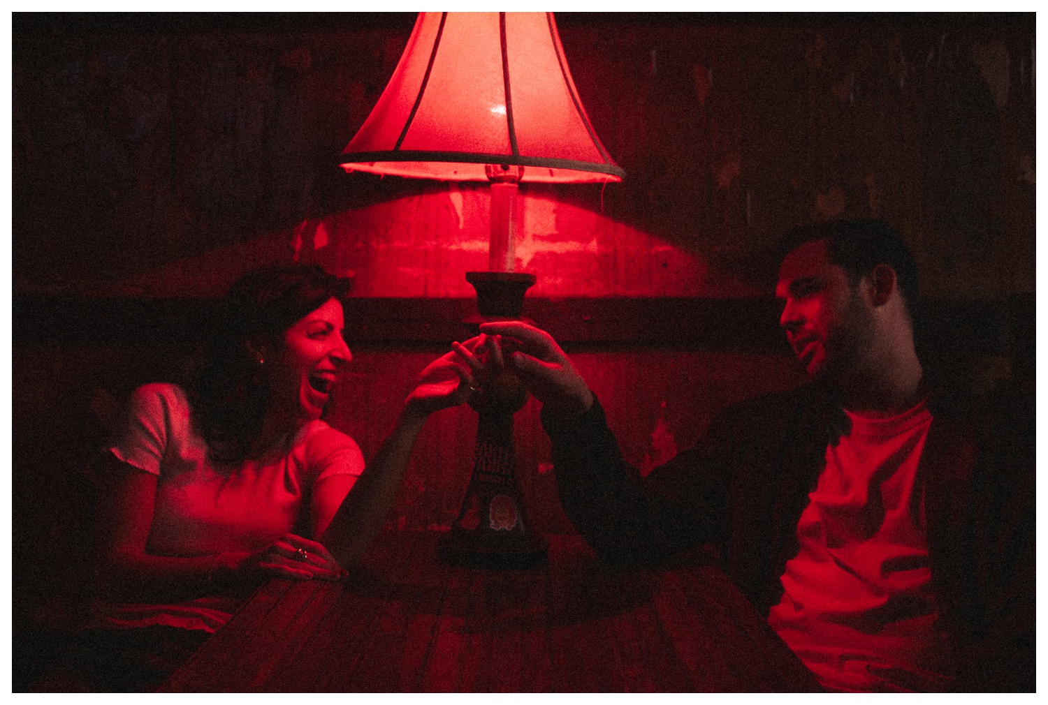 Engaged couple sitting in a bar under red light in Greenpoint Brooklyn. Brooklyn Wedding Photographer. Parr Photo Co