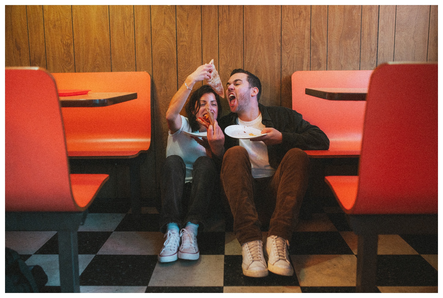 Engaged couple sitting on the floor at Paulie Gee's Slice Shop, sharing slices of pizza in Greenpoint Brooklyn. Brooklyn Wedding Photographer. Parr Photo co