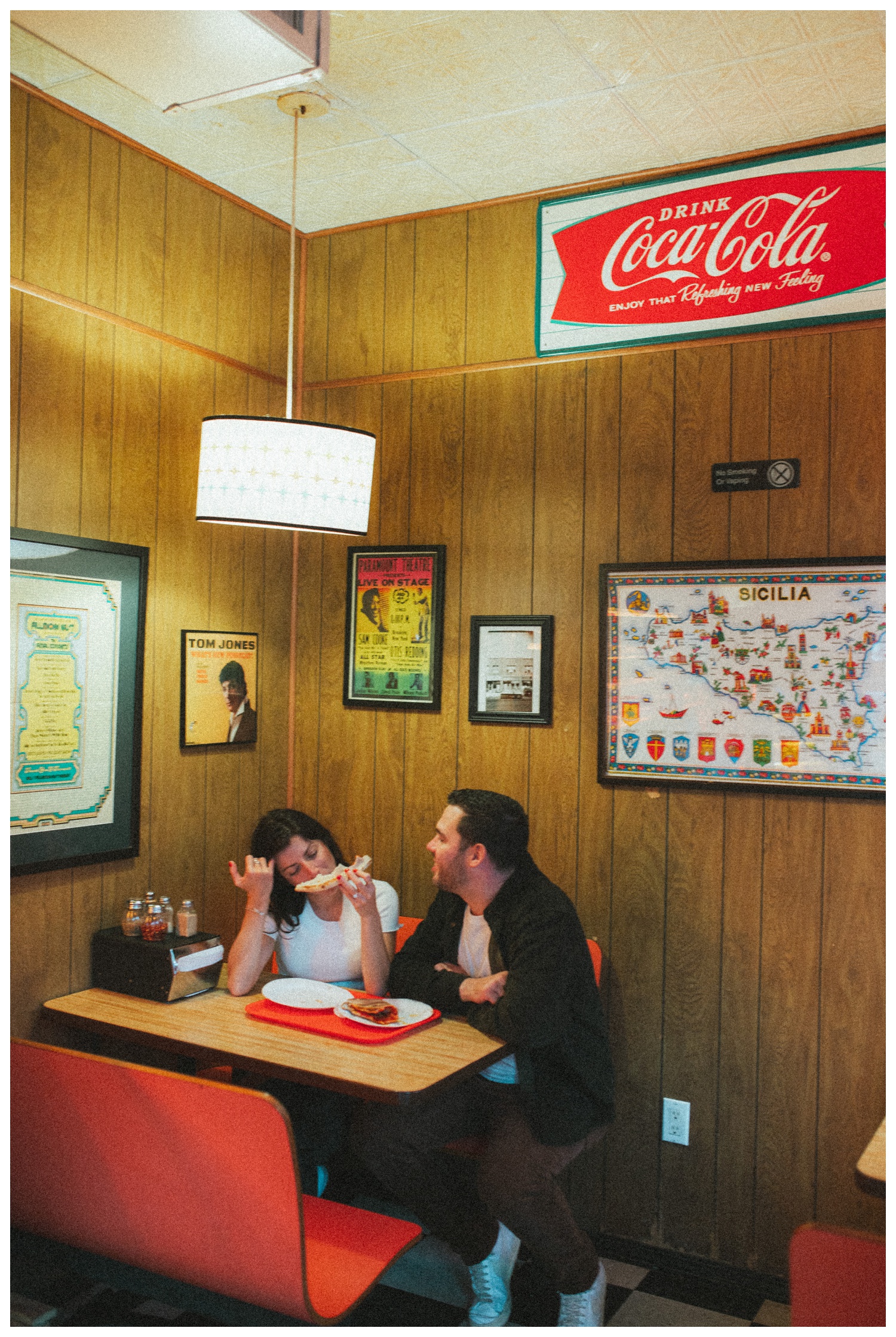 Engaged couple sitting on the floor at Paulie Gee's Slice Shop, sharing slices of pizza in Greenpoint Brooklyn. Brooklyn Wedding Photographer. Parr Photo co