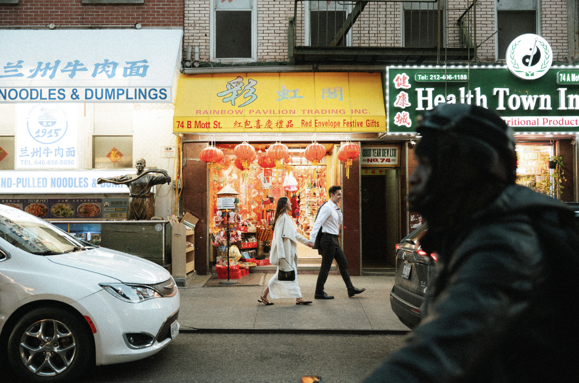 A bride and groom holding hands for their engagement session, walking through Chinatown on Mott St.