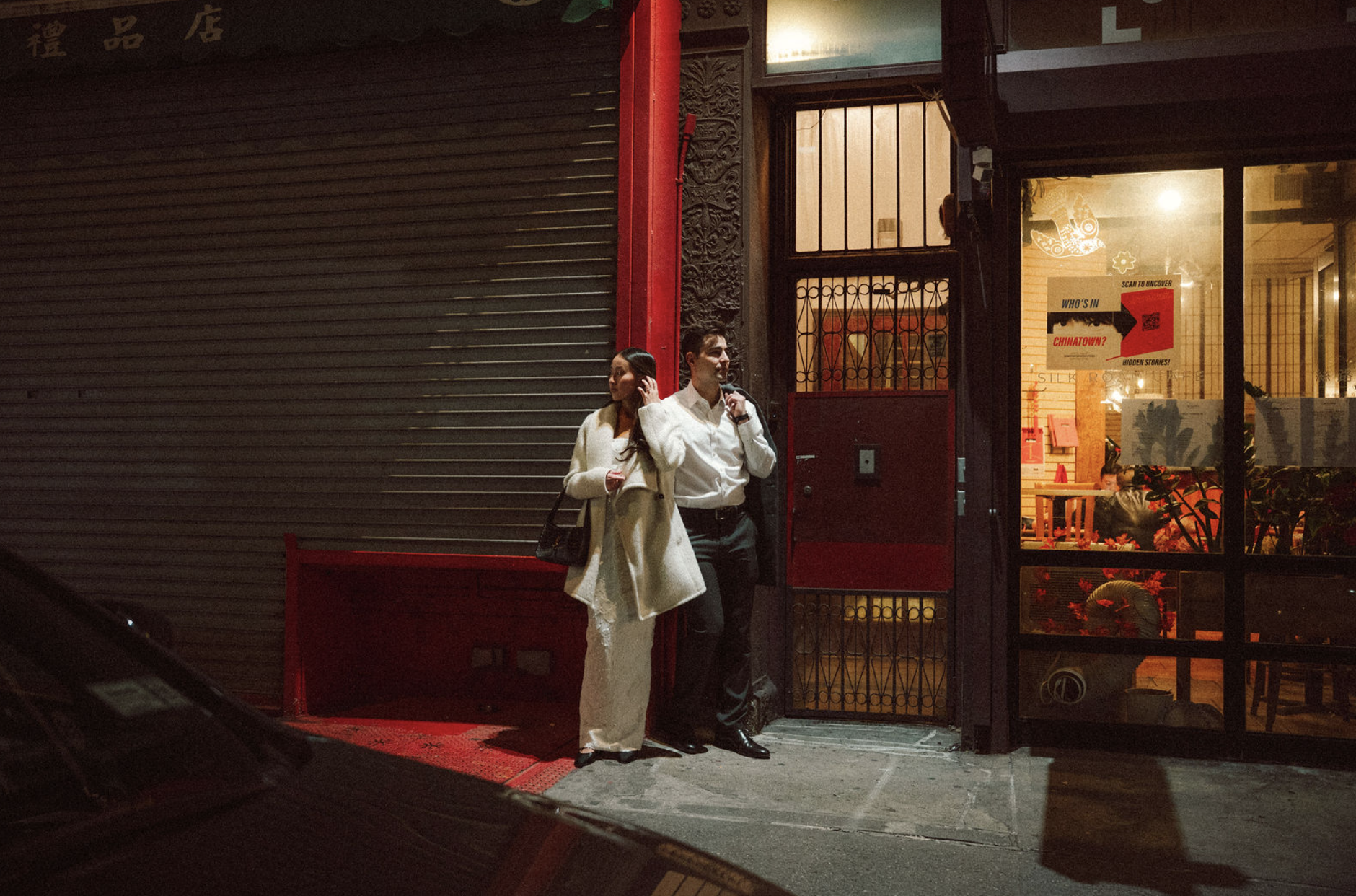 A bride and groom standing in Chinatown for their engagement session under a city light.