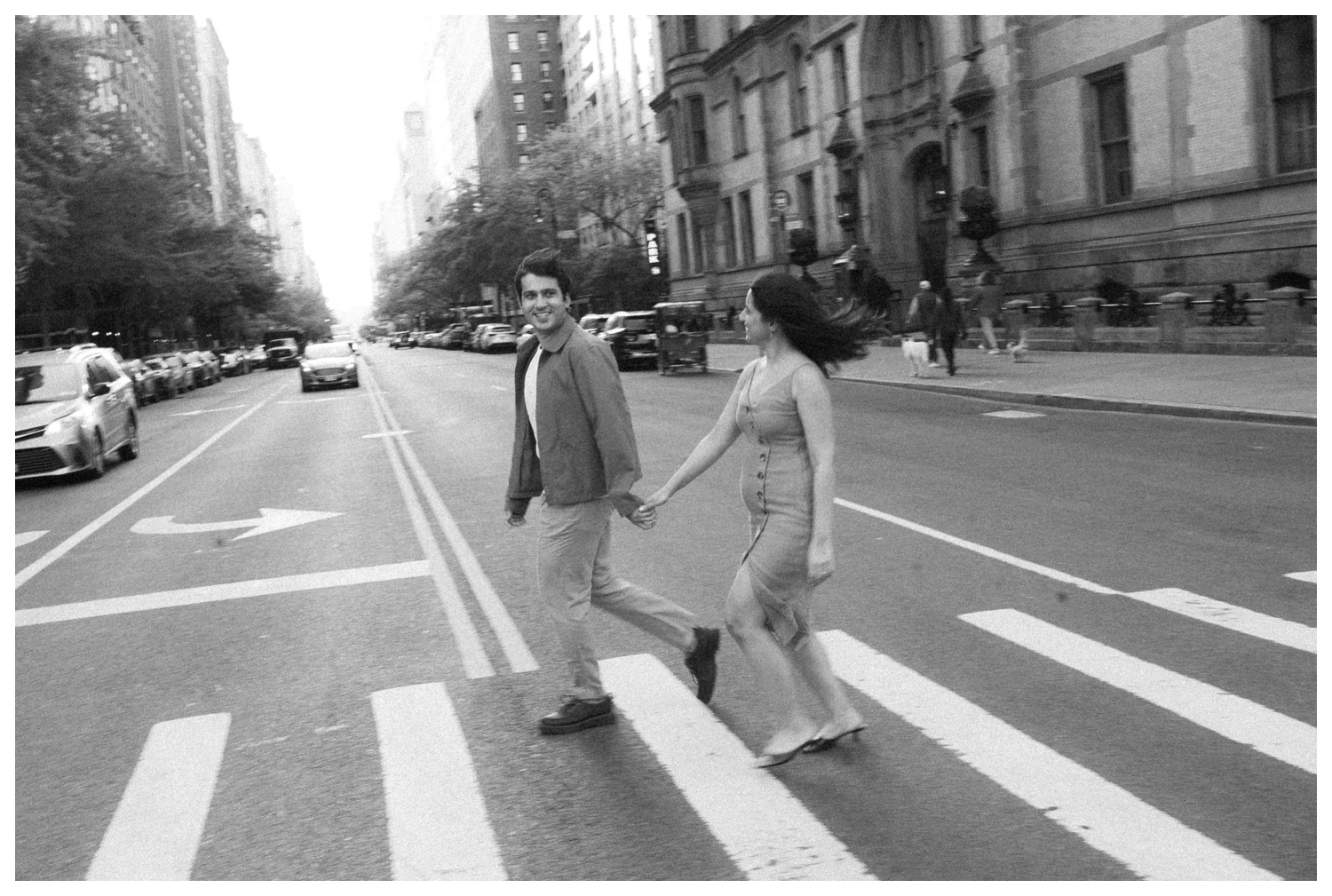 A couple running through the streets of NYC at their engagement session to make it to the subway